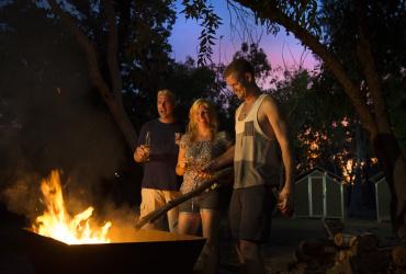 People enjoying standing by the fire while camping at Nitmiluk National Park