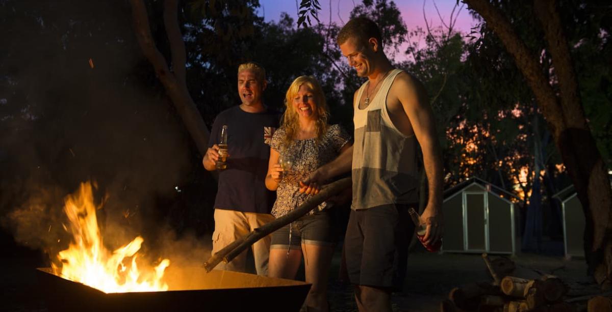 People enjoying standing by the fire while camping at Nitmiluk National Park